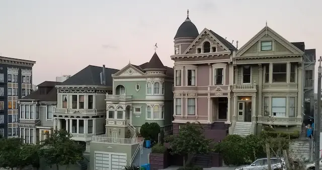 Victorian-style Painted Ladies in San Francisco at sunset, showcasing ornate architecture and pastel facades.
